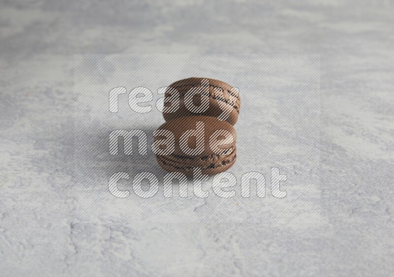 45º Shot of two Brown Dark Chocolate macarons  on white  marble background
