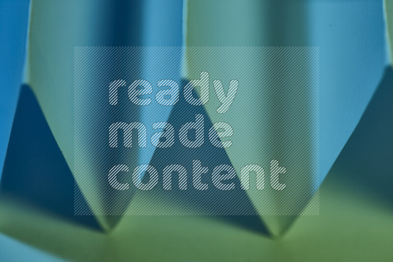 صورة مجردة مقربة تظهر طيات ورقية هندسية حادة بتدرجات اللون الأخضر والأزرق