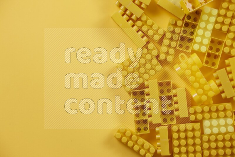 Yellow plastic building blocks on yellow background (kids toys)
