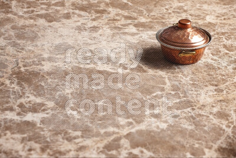 A small copper pot on beige marble background