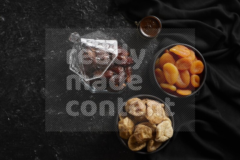 Dates in glass bowl with coffee and dried fruits in a dark setup