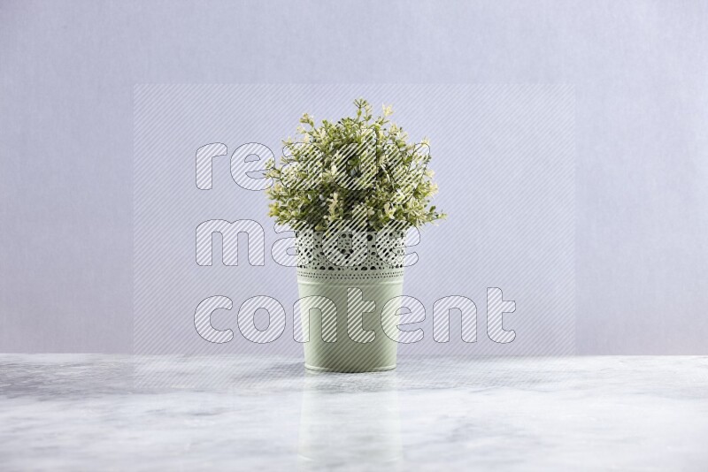 Artificial plant in green decorative pot on grey marble background