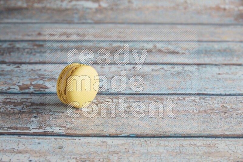 45º Shot of Yellow Lime macaron on light blue wooden background