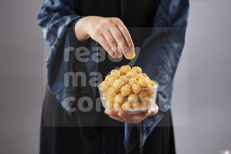 Woman in abaya holding different kinds of snacks in different positions