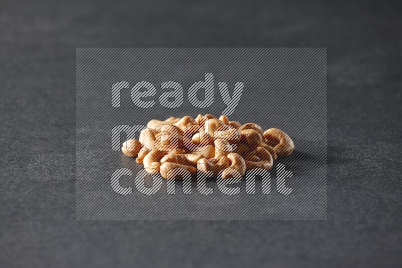 A bunch of cashews on a black background in different angles