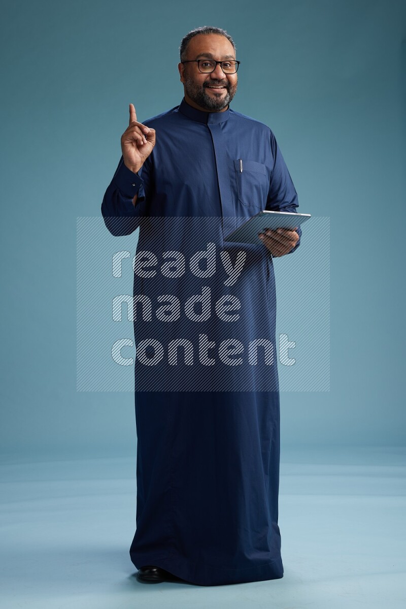Saudi Man without shimag Standing working on tablet on blue background