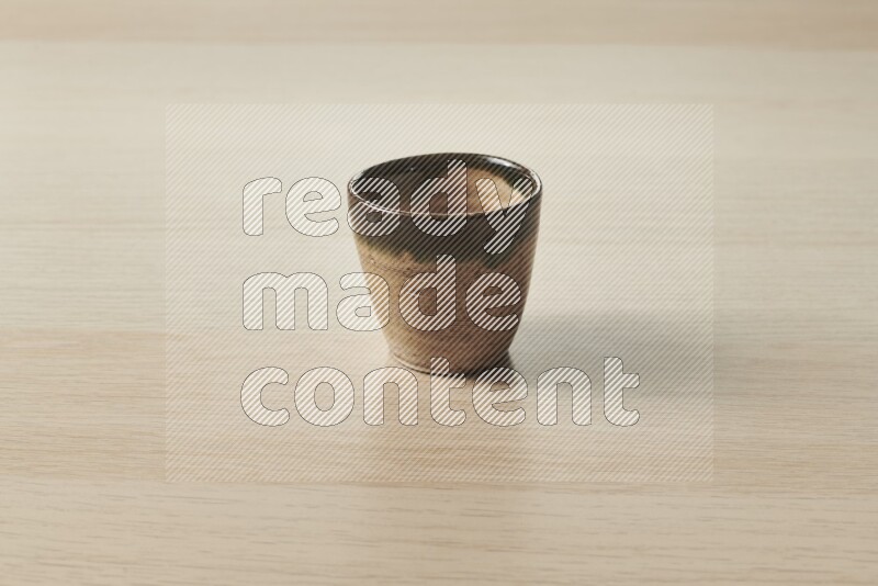 A pottery cup on light wooden background