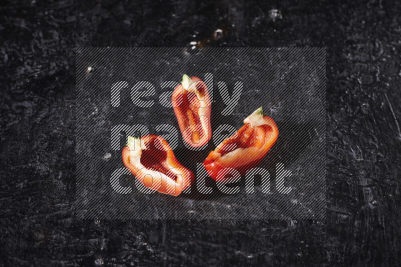 Red bell pepper slices on black background