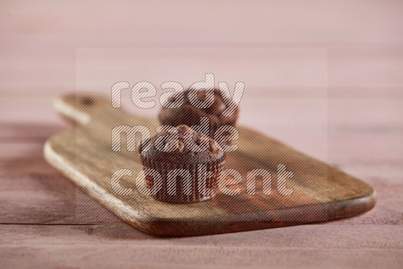 Chocolate mini cupcake topped with chocolate chips on a wooden board