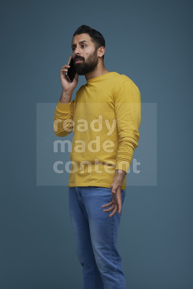 A man having a calling in a blue background wearing a yellow shirt
