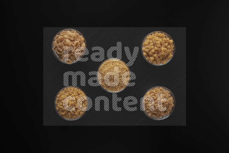 أنواع مختلفة من المعكرونة في أوعية زجاجية علي خلفية سوداء