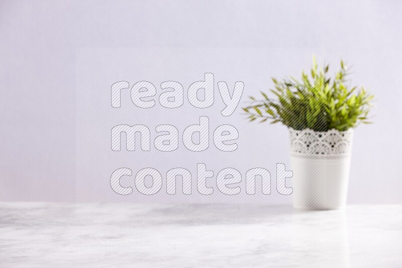 Artificial plant in white decorative pot on grey marble background