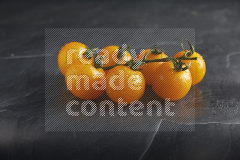 Yellow cherry tomato vein on a textured black slate background 45 degree