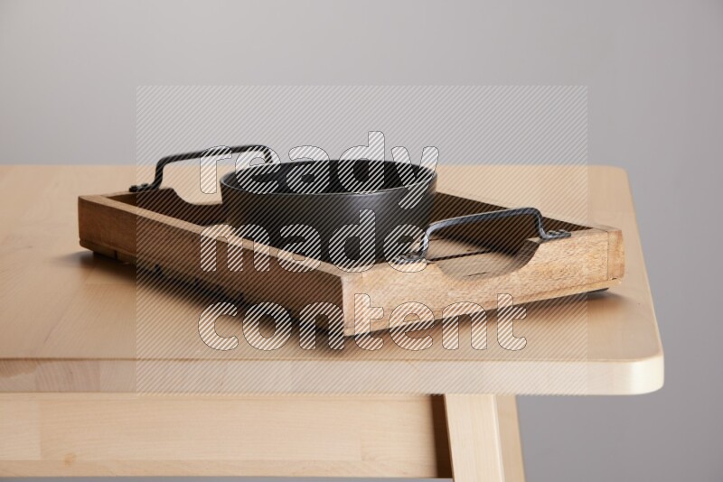 black bowl on a light colored rectangular wooden tray with handles
