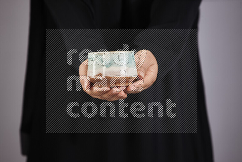 A woman in black abaya holding different pottery essentials in different positions