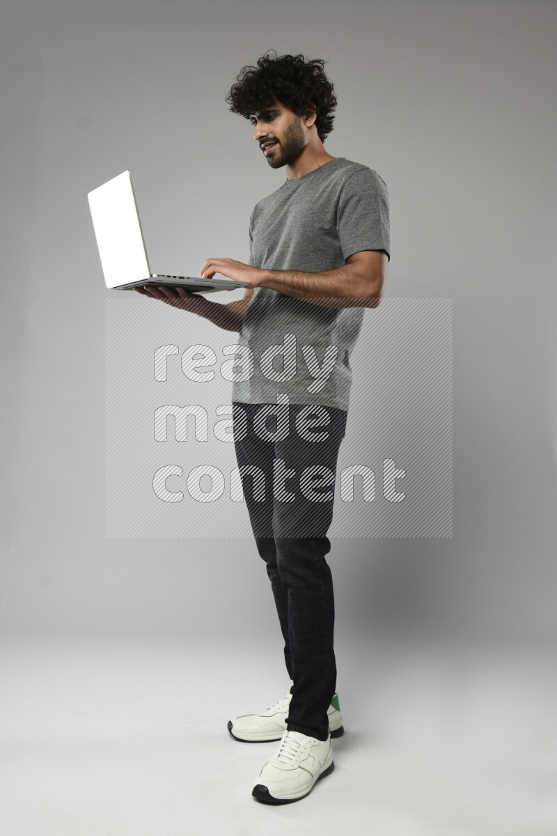 A man wearing casual standing and working on a laptop on white background
