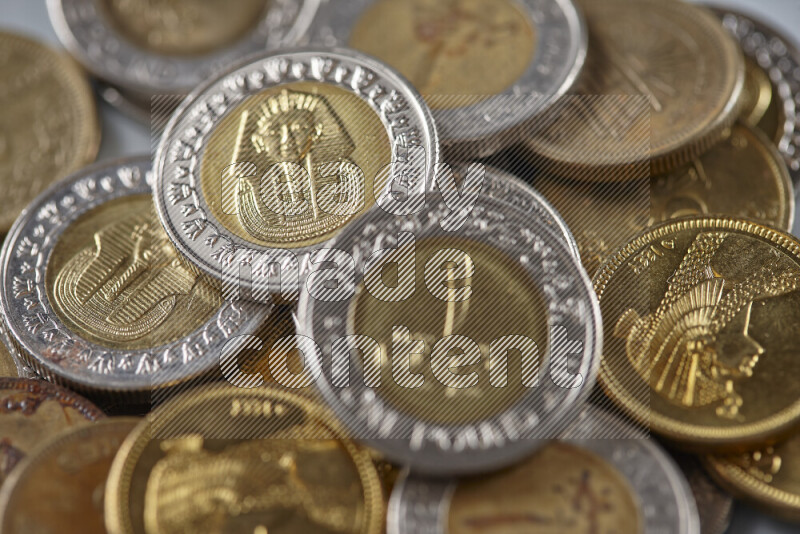 A close-up of scattered mixed Egyptian coins such as One pound, 50 and 25 piasters on grey background
