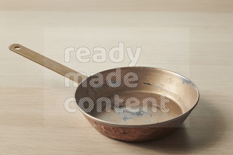 A small copper pan on light wooden background