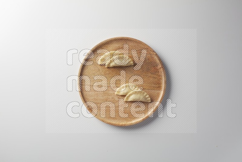 Four Sambosas on a wooden round plate on a white background