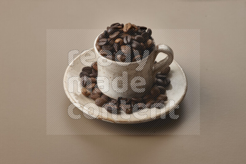 A beige pottery cup full of roasted coffee beans on beige background
