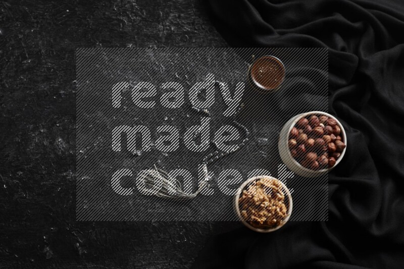 Nuts in pottery bowls with coffee in a dark setup