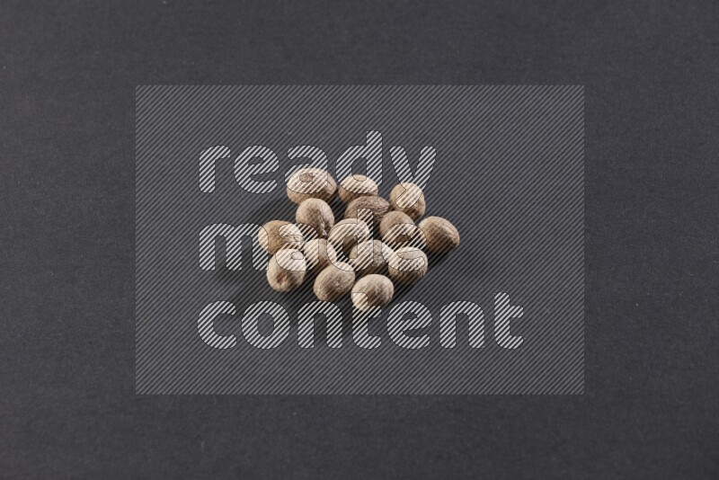 A bunch of whole nutmeg seeds on a black flooring