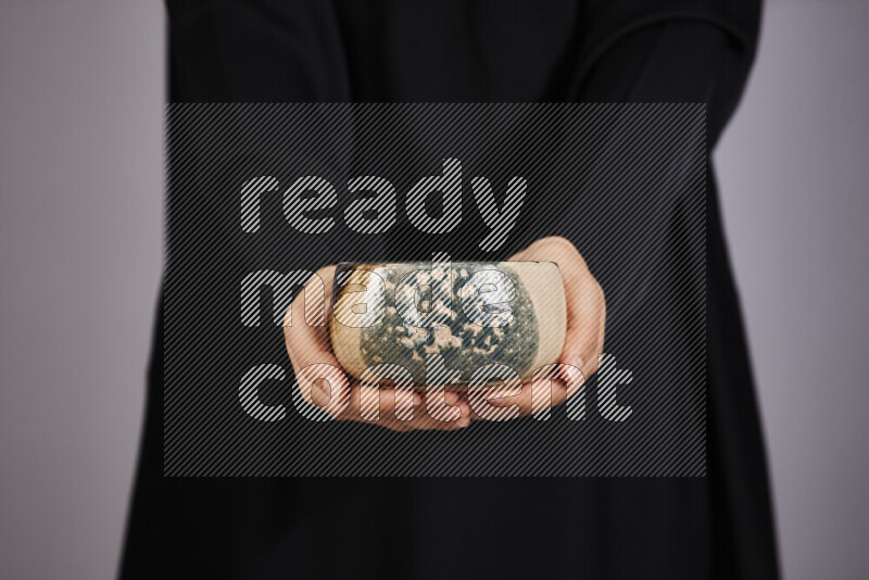A woman in black abaya holding different pottery essentials in different positions
