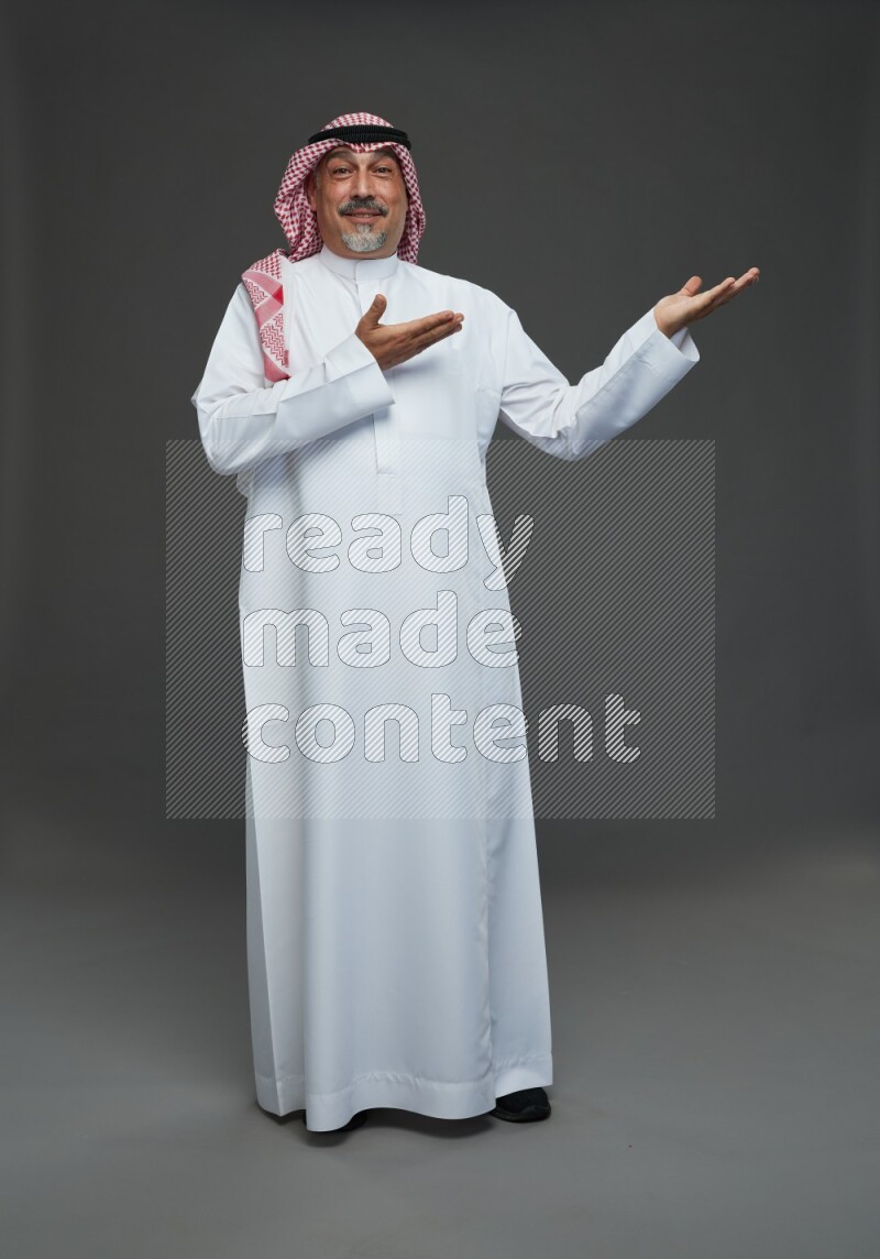 Saudi man with shomag Standing Interacting with the camera on gray background