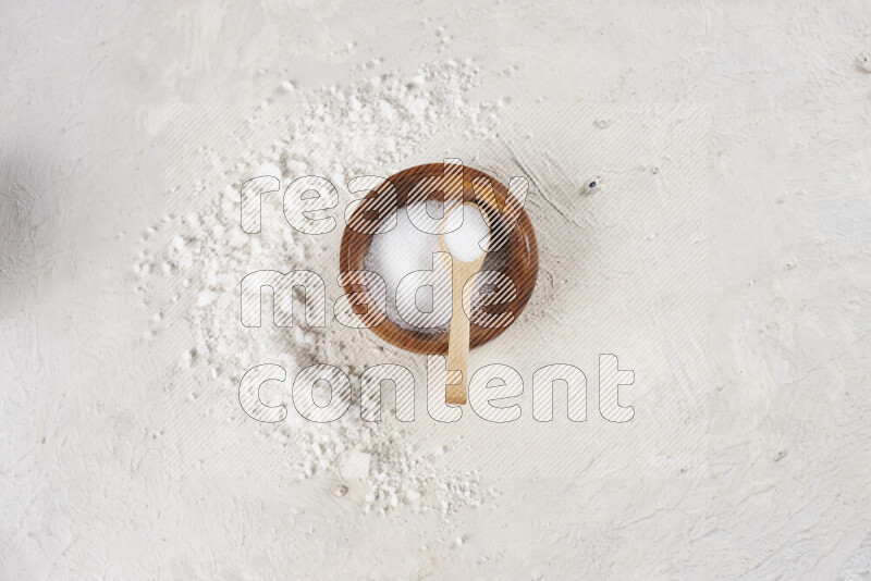 A pottery plate full of fine salt with bunch of coarse salt beside it on white background