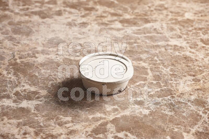 A white pottery bowl on beige marble background