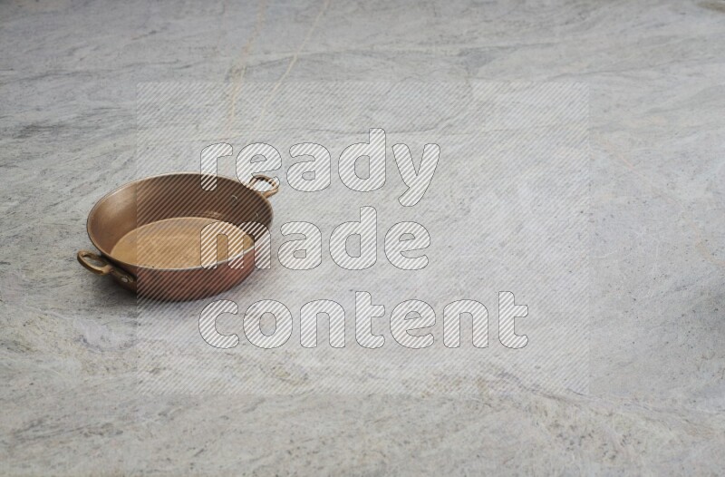 A small copper pan on grey marble background