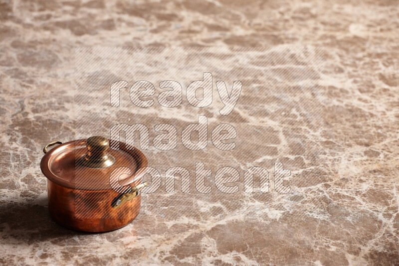 A small copper pot on beige marble background