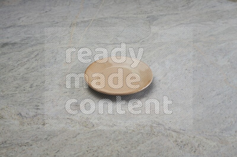 A beige pottery plate on grey marble background
