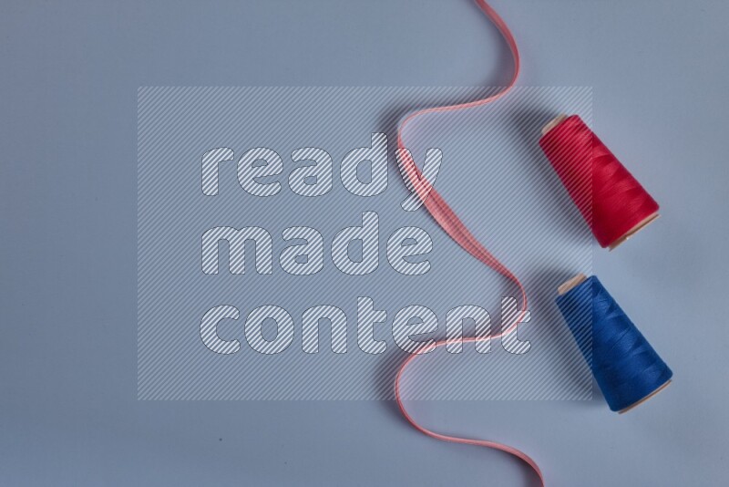 مجموعة من أدوات الخياطة والتفصيل زهرية اللون على خلفية زرقاء