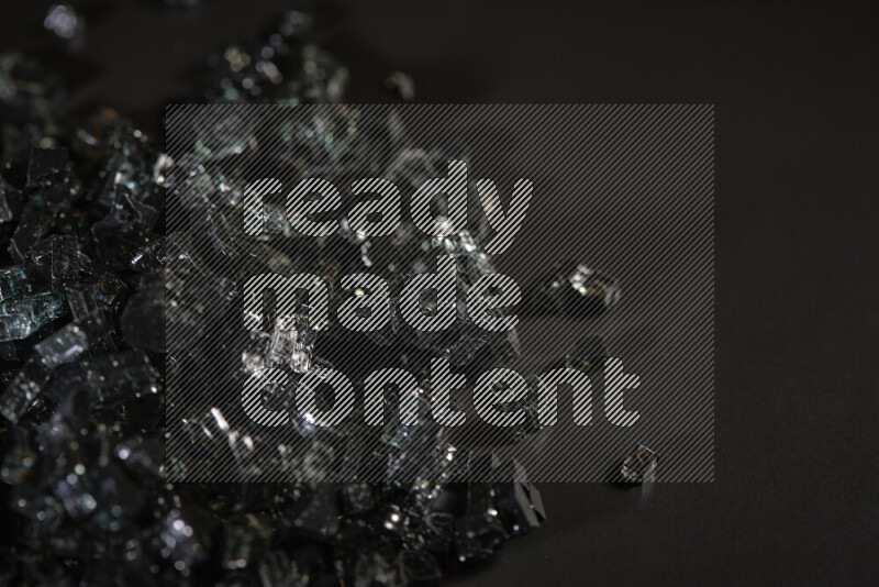 Transparent black fragments of glass scattered on a black background