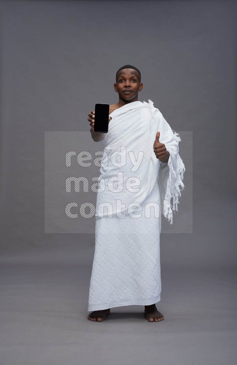 A man wearing Ehram Standing showing phone to camera on gray background