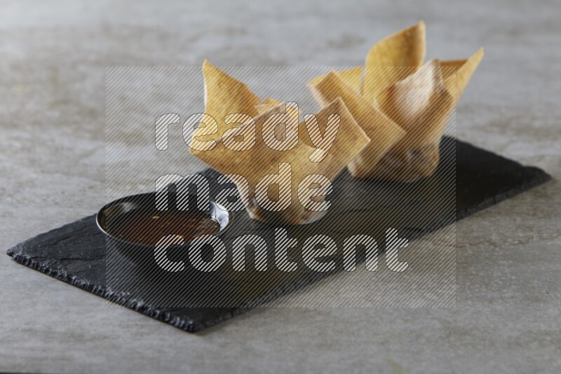 wonton cups with soy sauce ramkin on rectangle slate on grey textured counter top