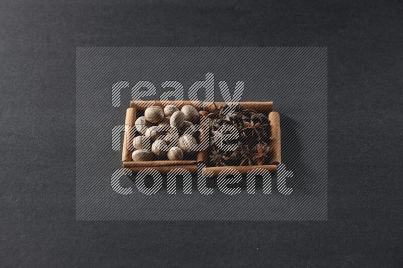2 squares of cinnamon sticks full of nutmeg and star anise on black flooring