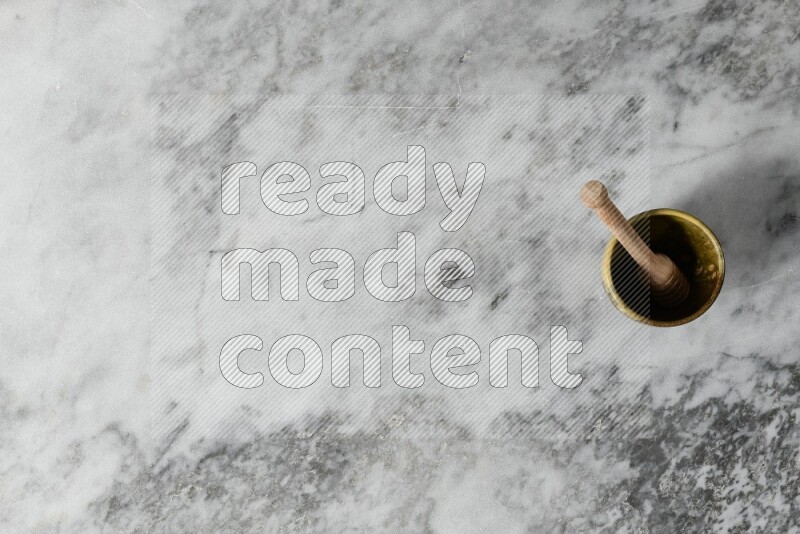 Multicolored pottery cup with wooden honey dipper in it on grey marble background