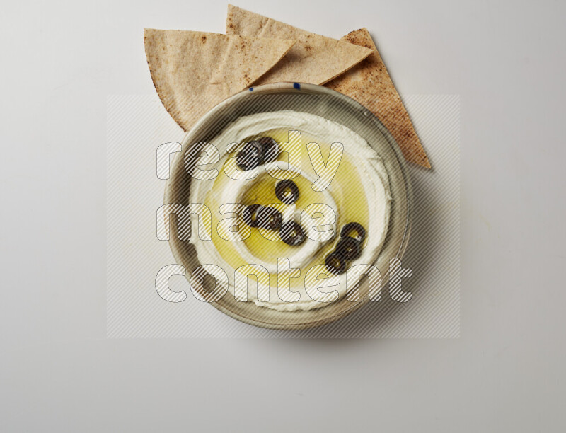 Lebnah garnished with sliced olives in a grey pottery plate on a white background