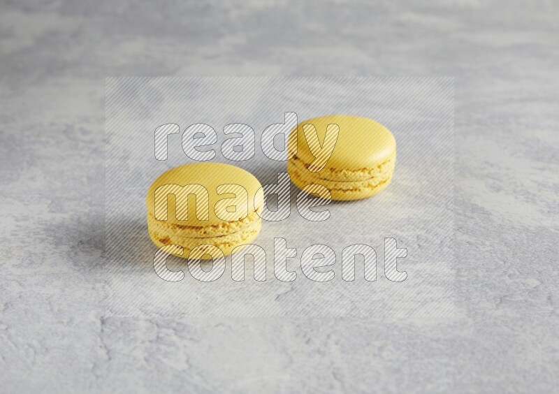 45º Shot of two Yellow Lemon macarons  on white  marble background