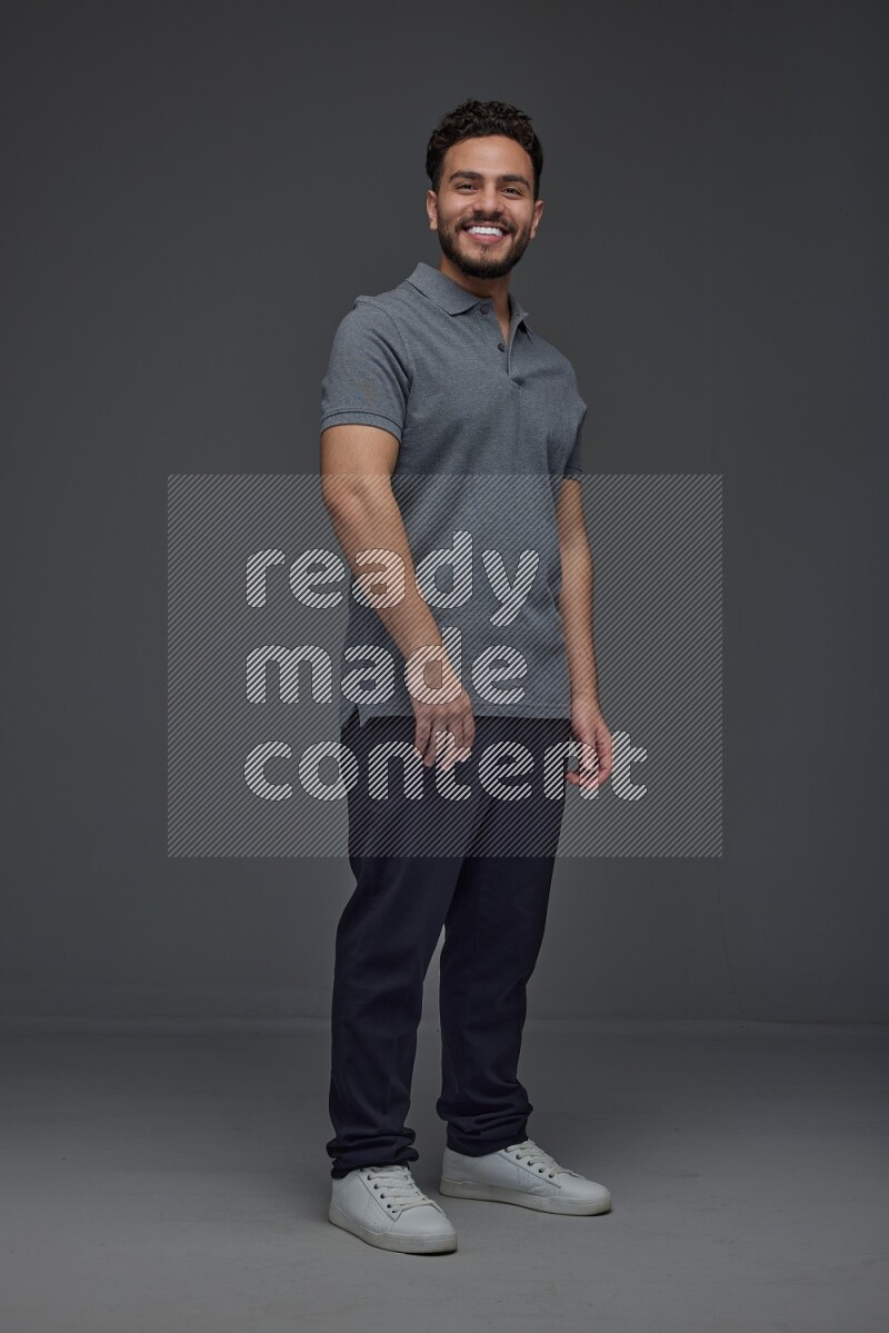 A man wearing casual standing and making multi hand gestures eye level on a gray background