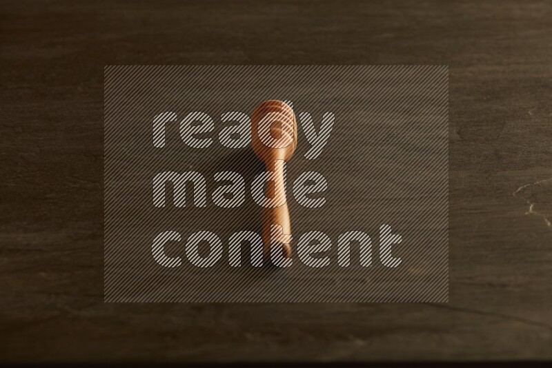 Wooden honey dipper on black slate background