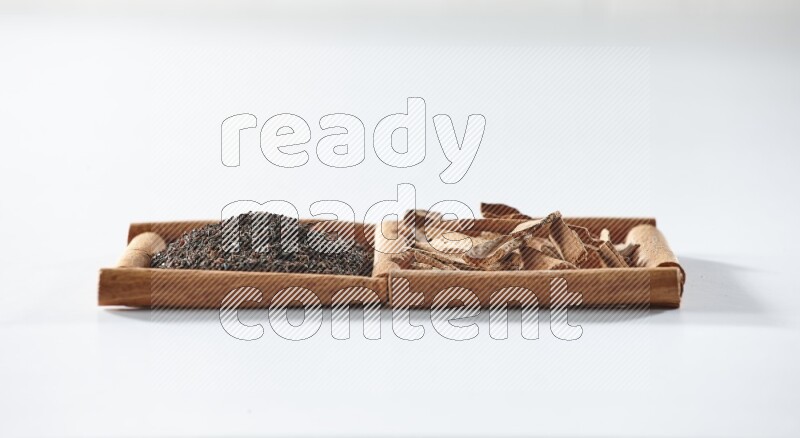 مربعان من أعواد القرفة ممتلئان بالشاي الأسود وقطع القرفة علي خلفية بيضاء