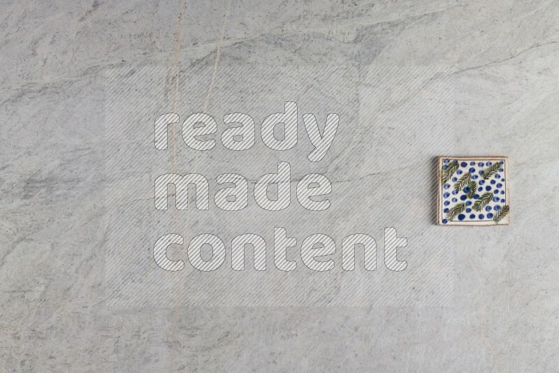 A decorative pottery coaster on grey marble background