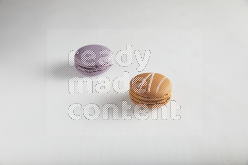 45º Shot of of two assorted Brown Irish Cream, and Purple Blueberry macarons on white background