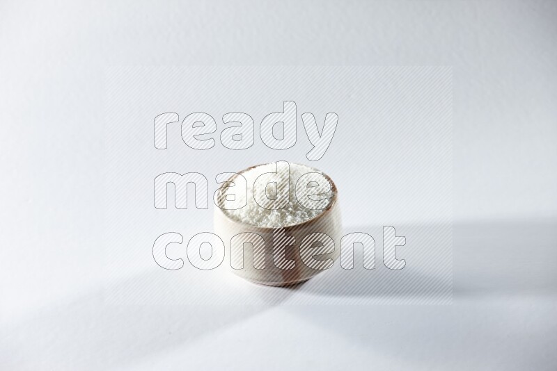 A beige ceramic bowl full of desiccated coconut on a white background in different angles