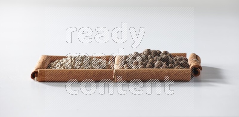 2 squares of cinnamon sticks full of white pepper and allspice on white flooring