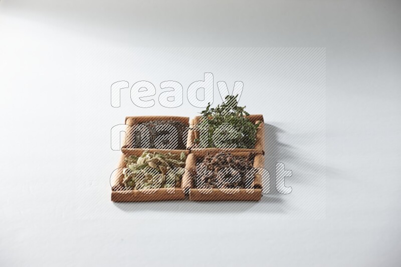 4 مربعات من أعواد القرفة ممتلئة بالشاي والهيل والنعناع والقرنفل على أرضية بيضاء