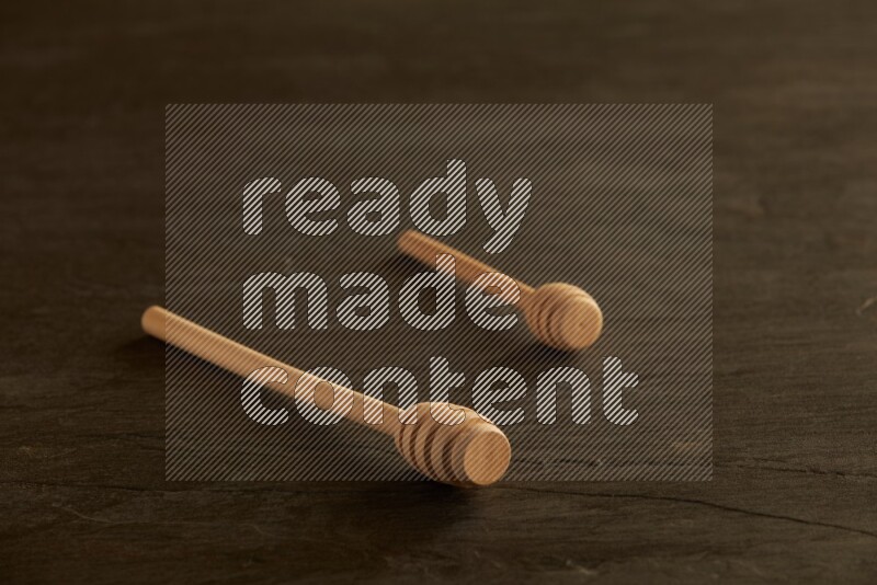 Wooden honey dipper on black slate background